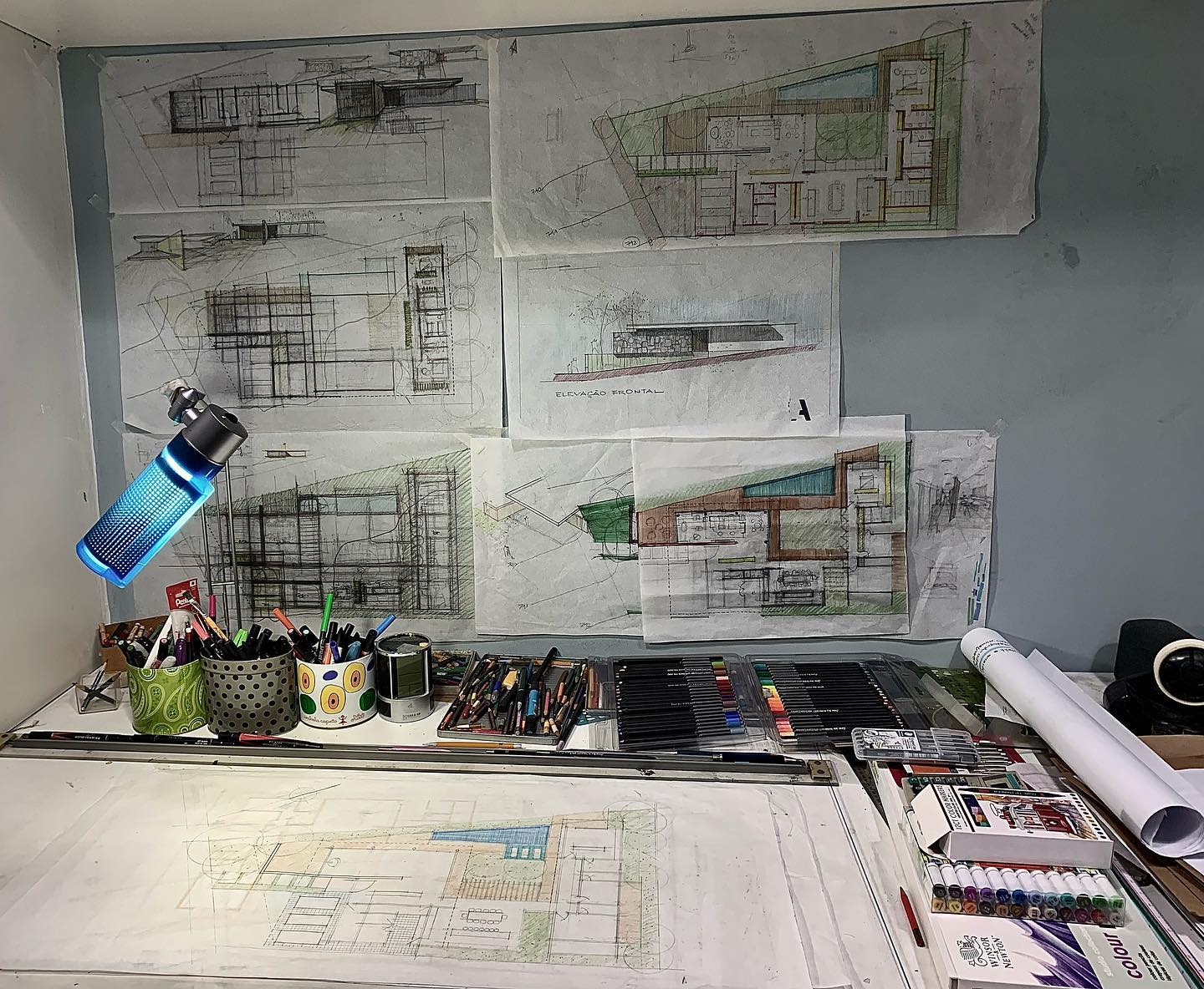 Mesa de trabalho com croquis e desenhos à mão de projetos, marca do escritório